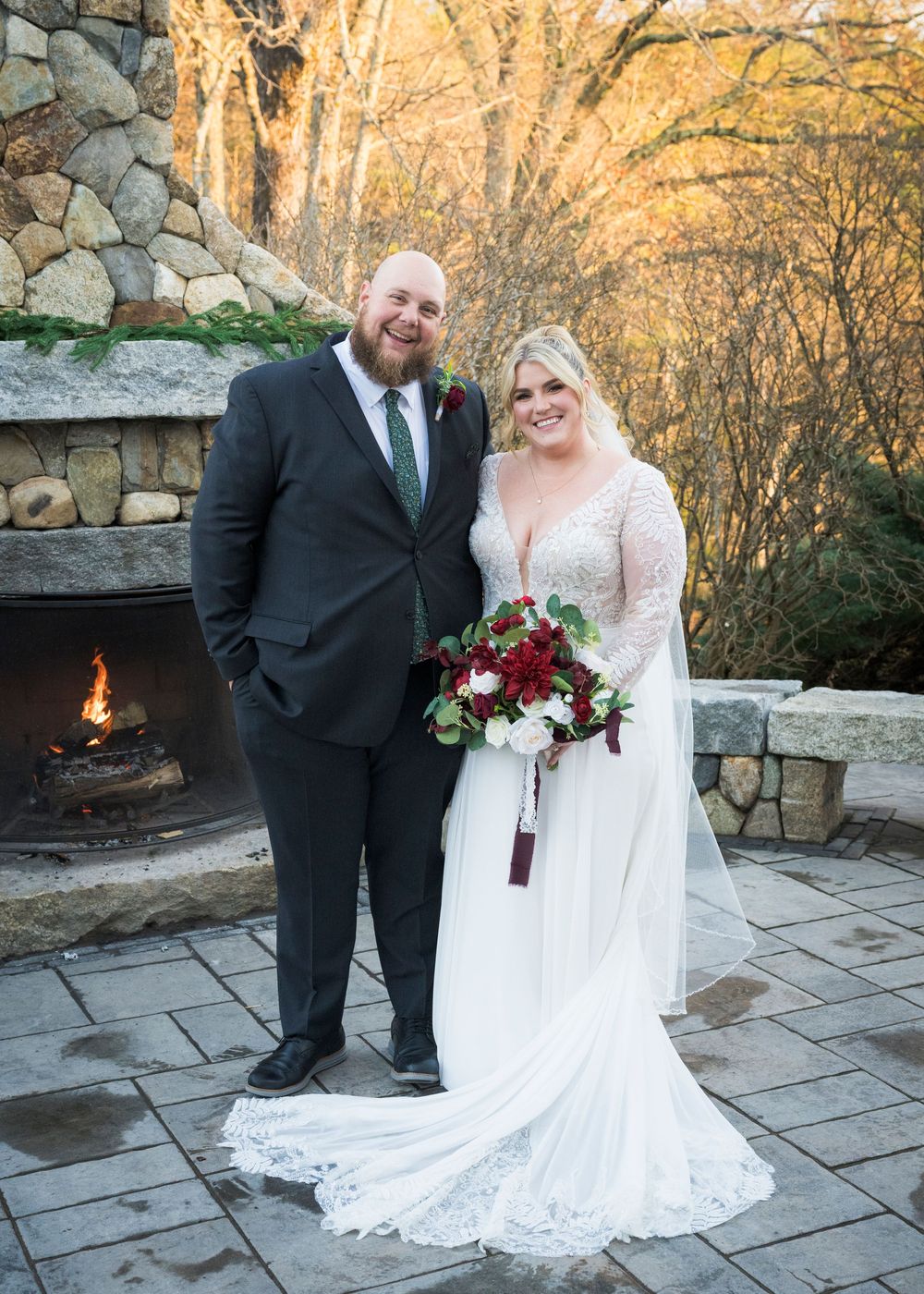 Elegant wedding couple poses on stone patio during sunset ceremony.