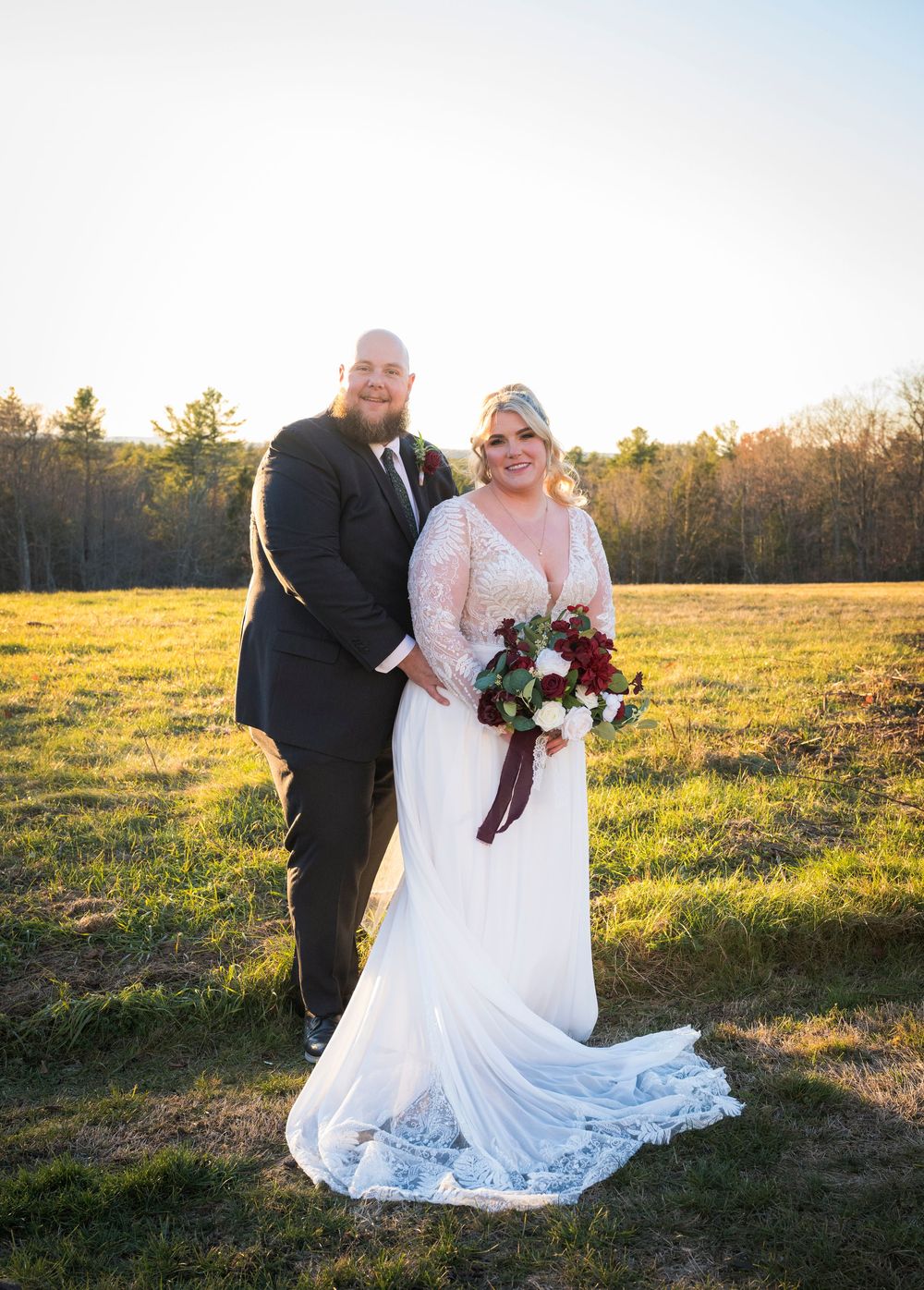 Wedding couple standing in golden sunlit field during sunset portrait session.