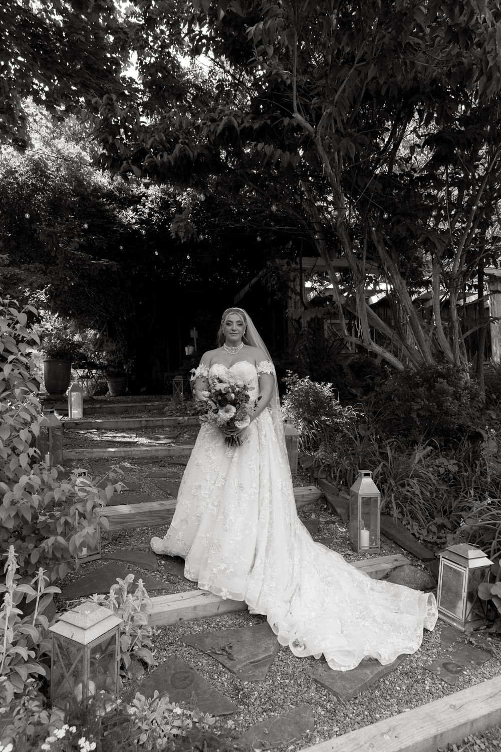 A figure in a flowing white wedding dress and veil stands solemnly among gravestones in a cemetery.