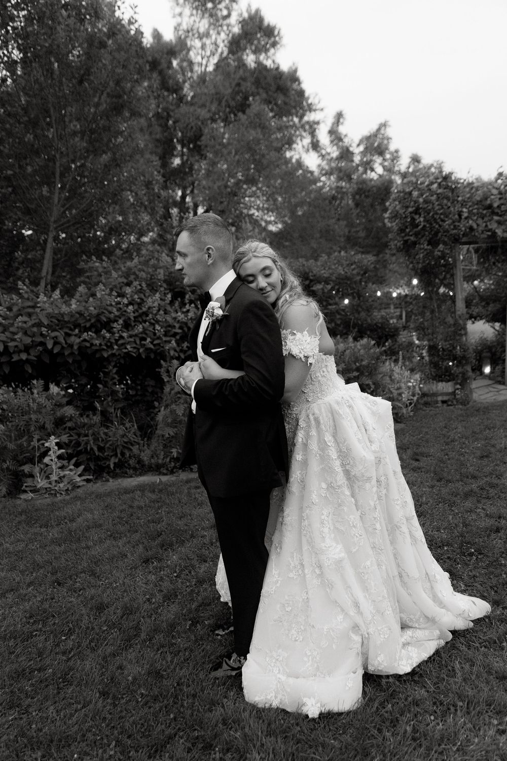 A romantic black and white photo series of a couple in wedding attire sharing intimate moments in a garden setting.