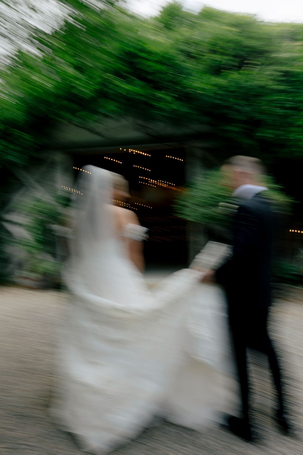 Motion-blurred wedding scene with trees and string lights creating an artistic effect.