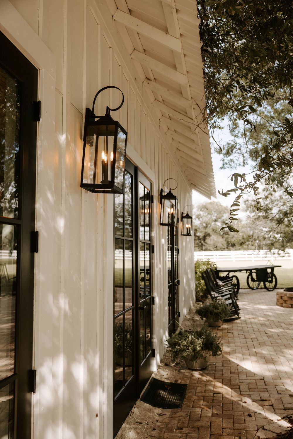 White barn exterior with black lanterns and windows creating a classic farmhouse aesthetic.