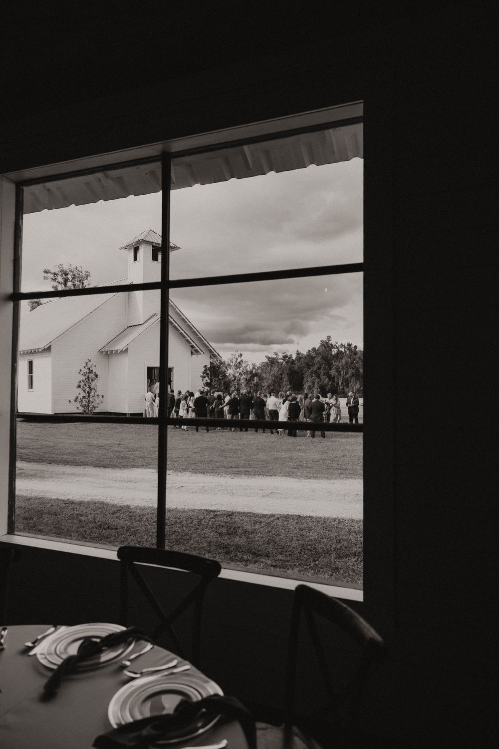 Black and white panoramic window view from inside a barn venue.
