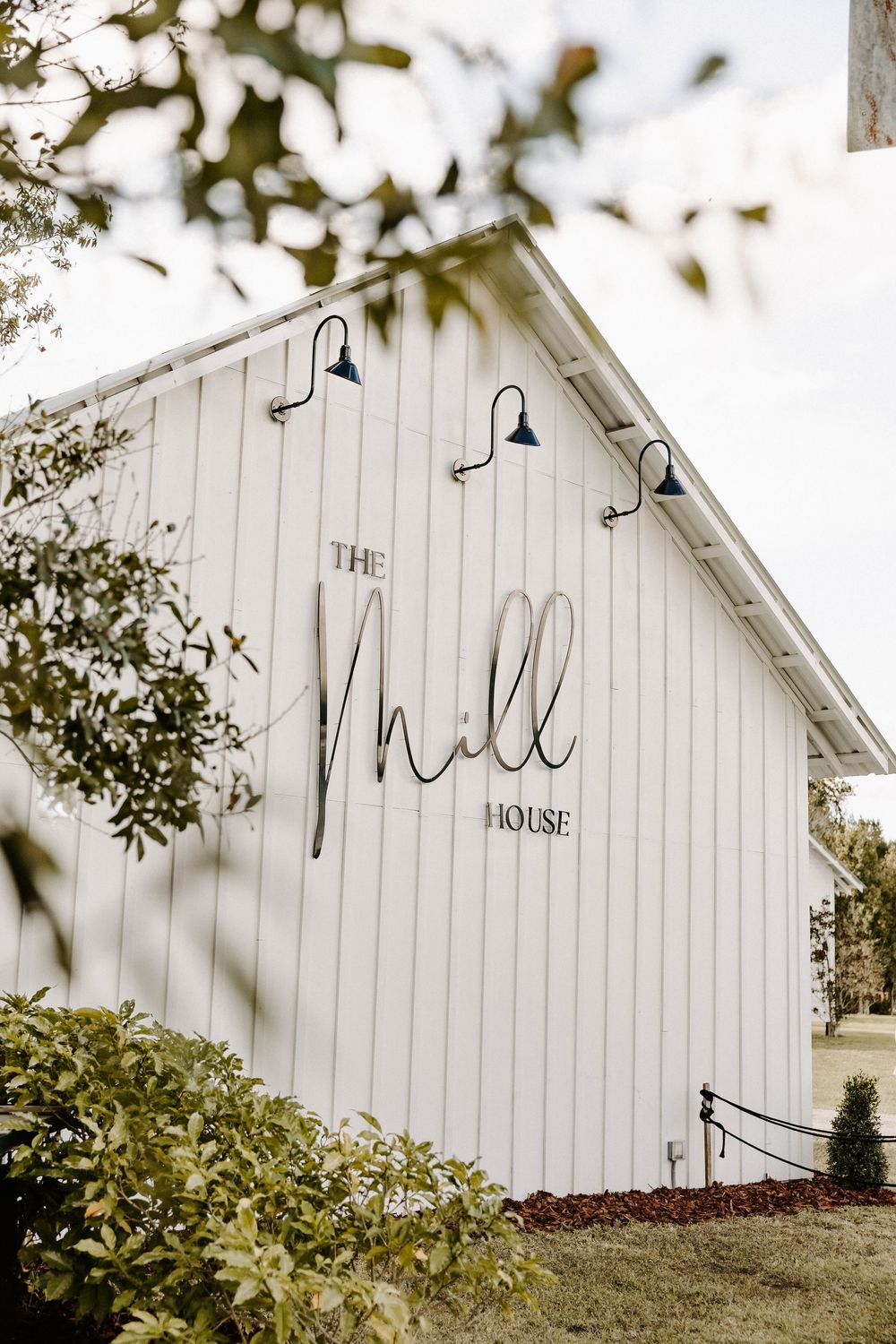 White barn-style event venue with 'The Mill House' signage on the exterior wall.