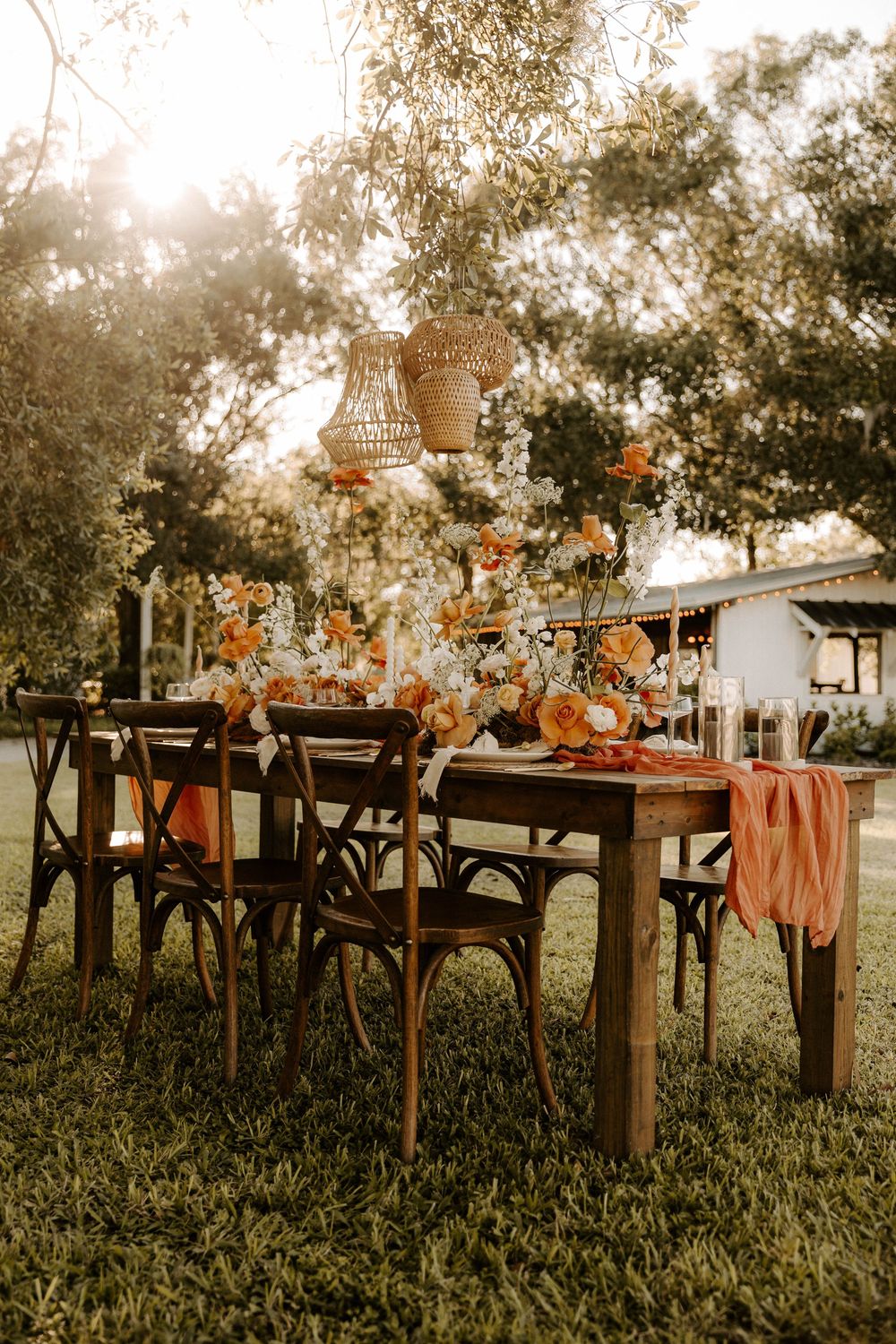 Long wooden tables set for outdoor dining with terracotta accents and floral arrangements.