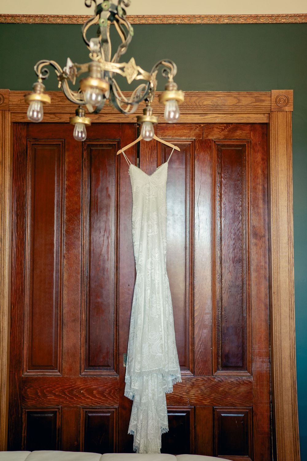 A white wedding dress hangs elegantly against dark wooden paneled walls.