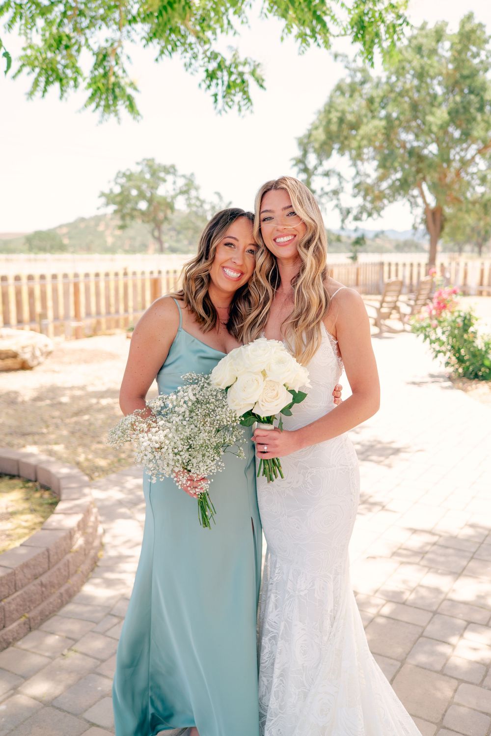 Bridesmaids in light blue dresses share joyful moments with bride outdoors.