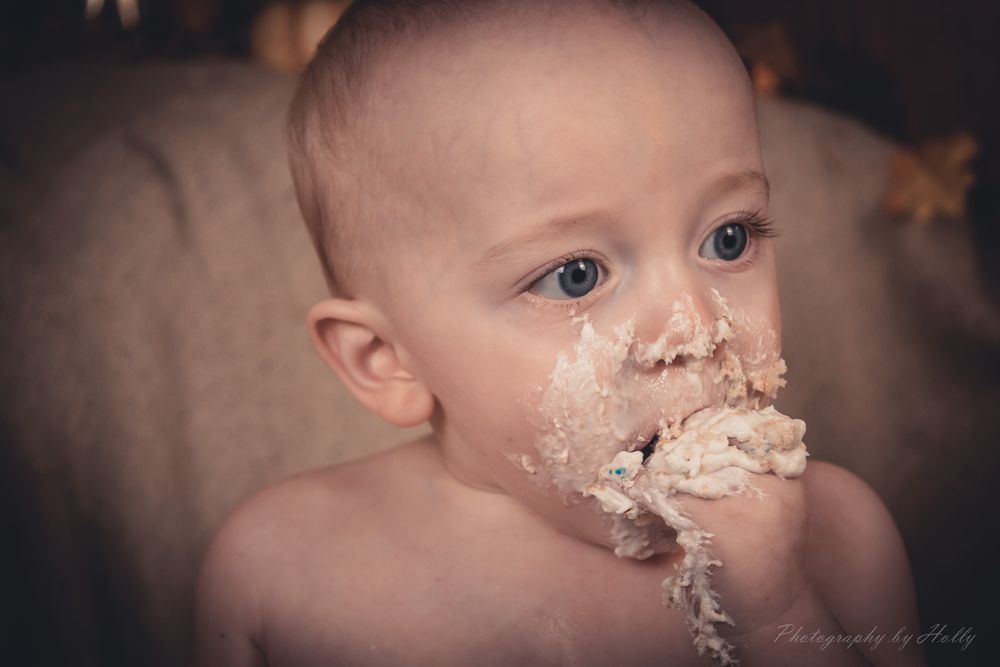 Close up view of a cake smash photoshoot with white frosting and sprinkles.
