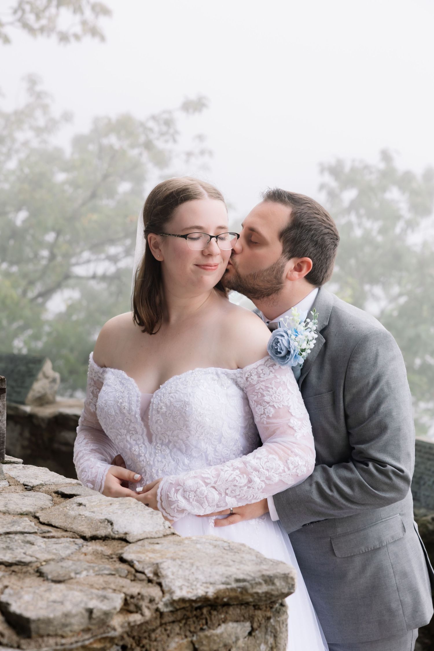 A romantic couple shares a tender moment on a rocky cliff edge, wearing wedding attire. South Carolina photographer