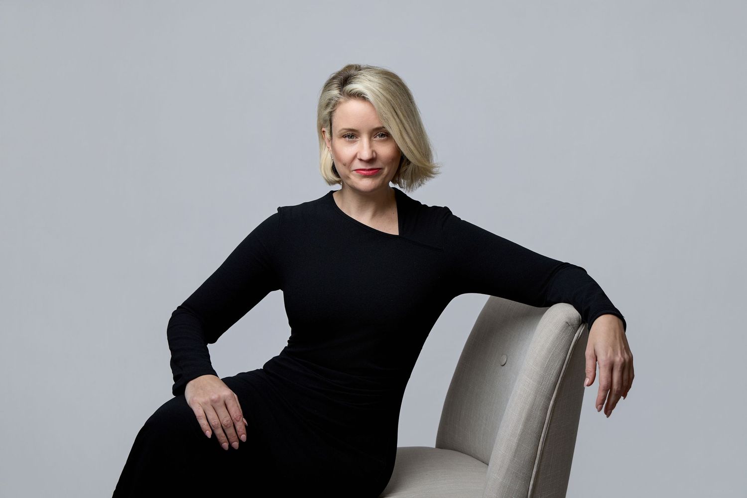 A person in a black dress poses elegantly against a gray backdrop in a series of professional studio portraits.