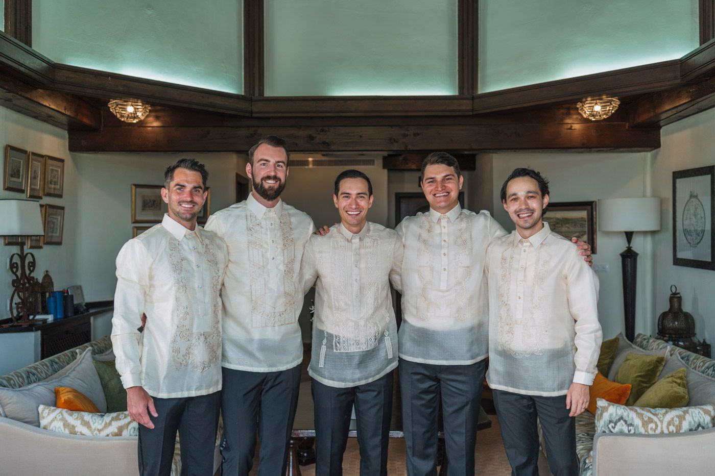 Five people in white dress shirts stand together in a modern interior space with curved windows.