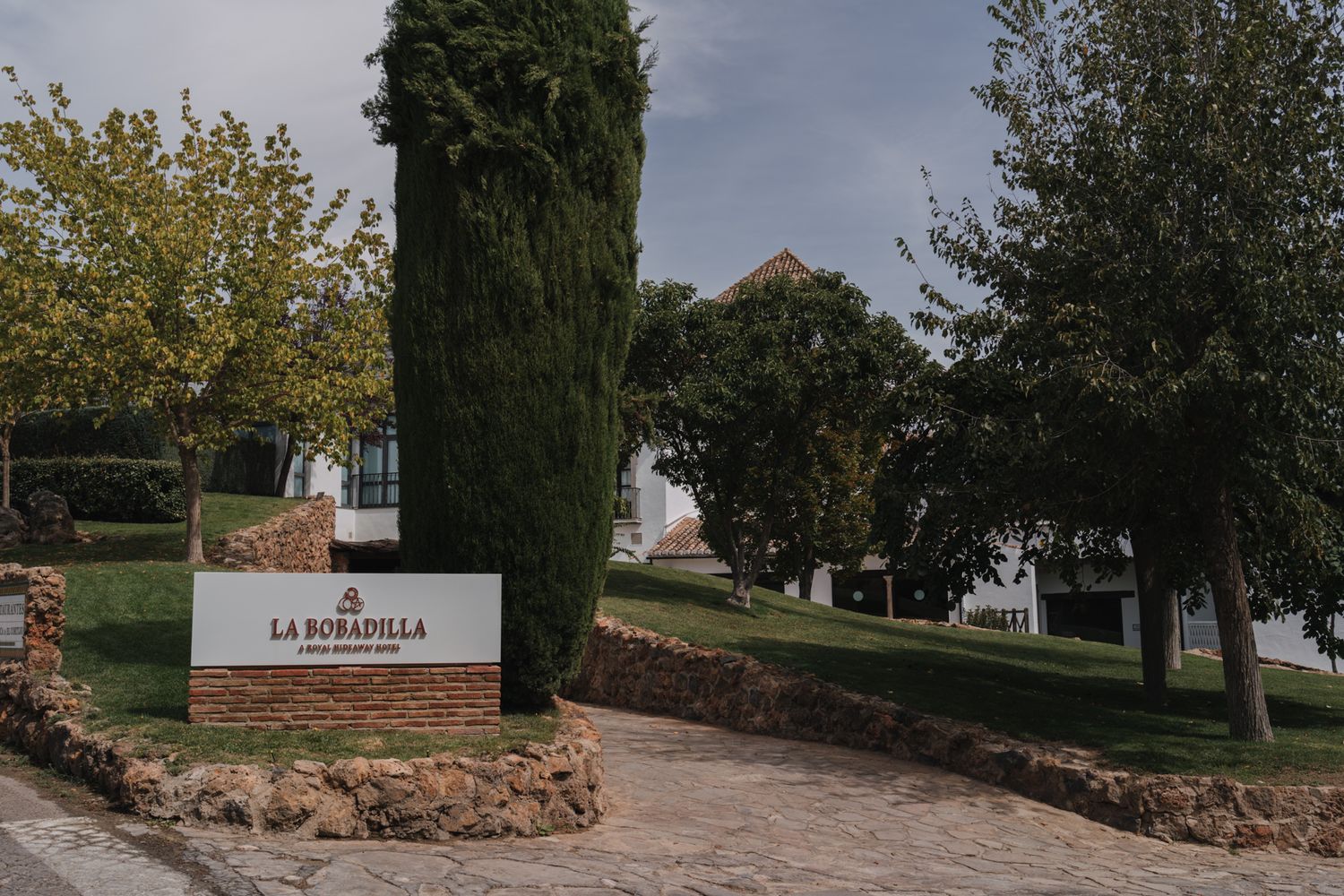 Entrance sign to a property marked 'La Esperanza' with tall cypress trees and stone landscaping.