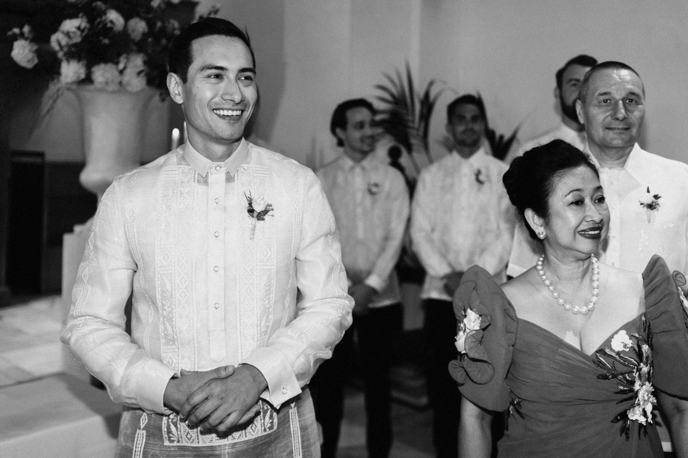 Black and white photo of a joyful wedding scene showing people in formal attire at a festive celebration.