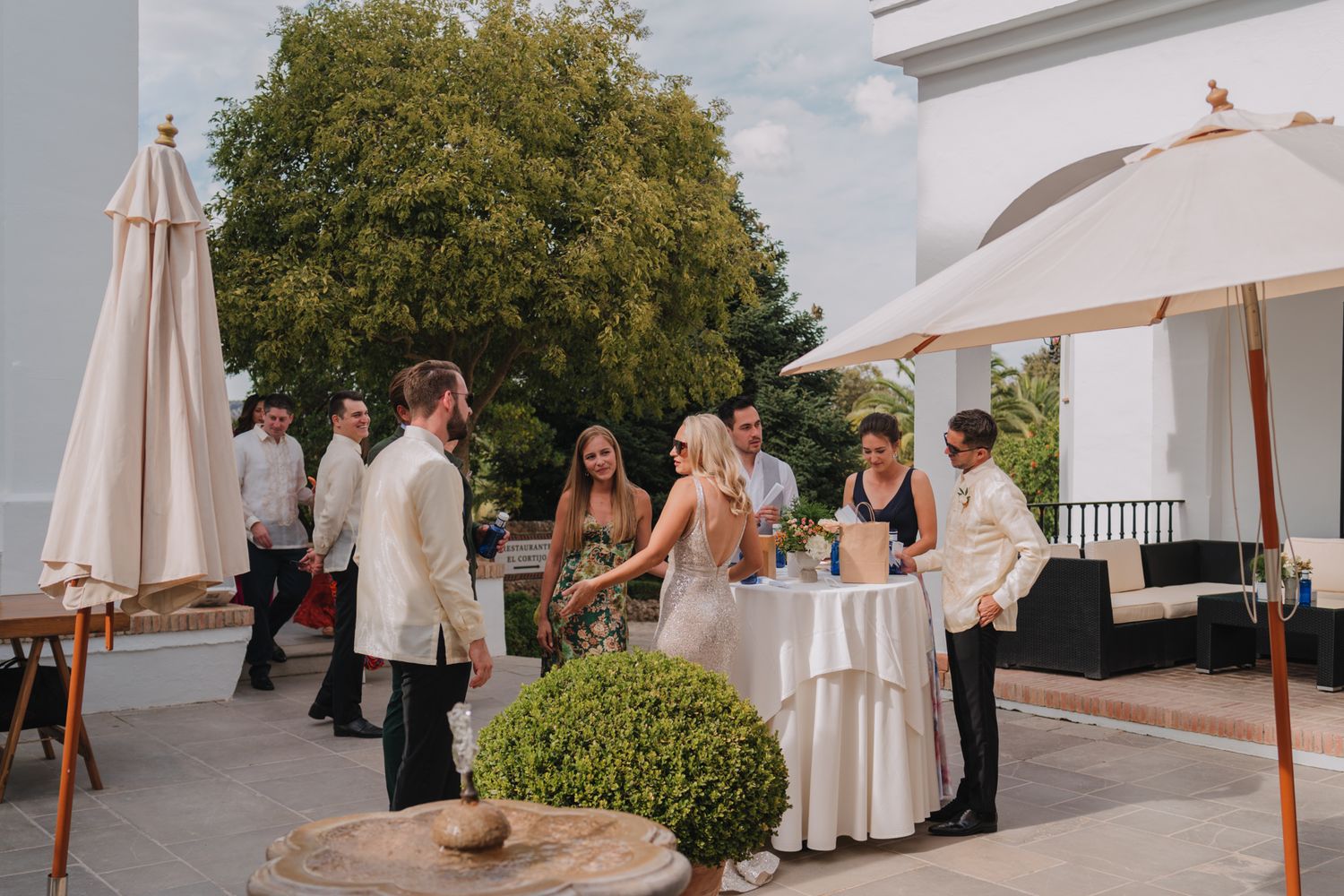 Elegant outdoor reception gathering on a terrace with white umbrellas and tablecloths.