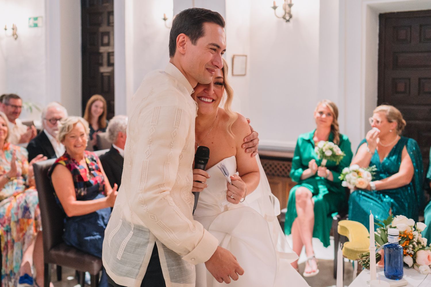 A tender moment between newlyweds during their first dance while guests look on.