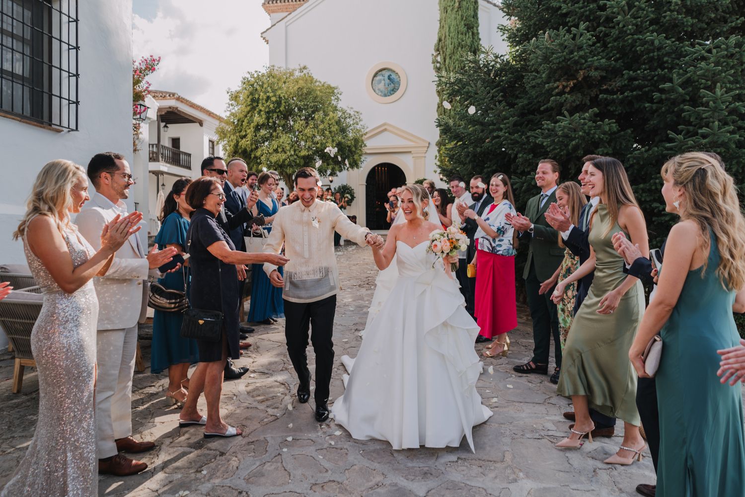 Wedding celebration with guests gathered outside a Mediterranean-style building creating a festive atmosphere.