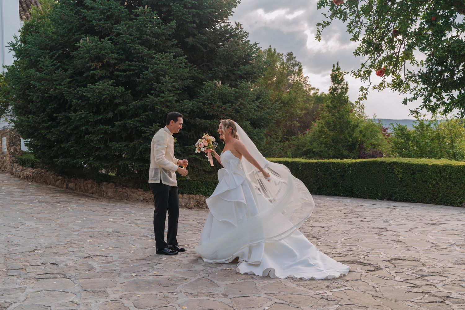 Romantic scene of a couple in a garden setting with stone patio during an outdoor wedding celebration.
