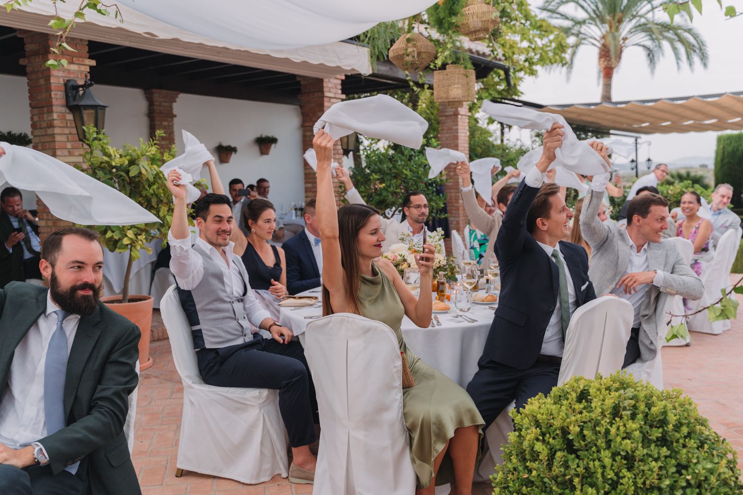 Wedding guests celebrating enthusiastically during outdoor reception.
