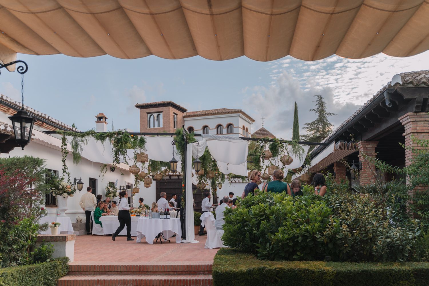 Outdoor wedding reception venue with Mediterranean style architecture featuring covered patio and decorative landscaping.
