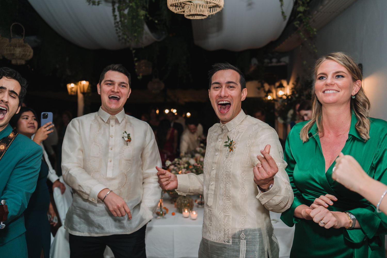 Wedding guests in traditional Filipino formal attire share joyful moments during the reception.