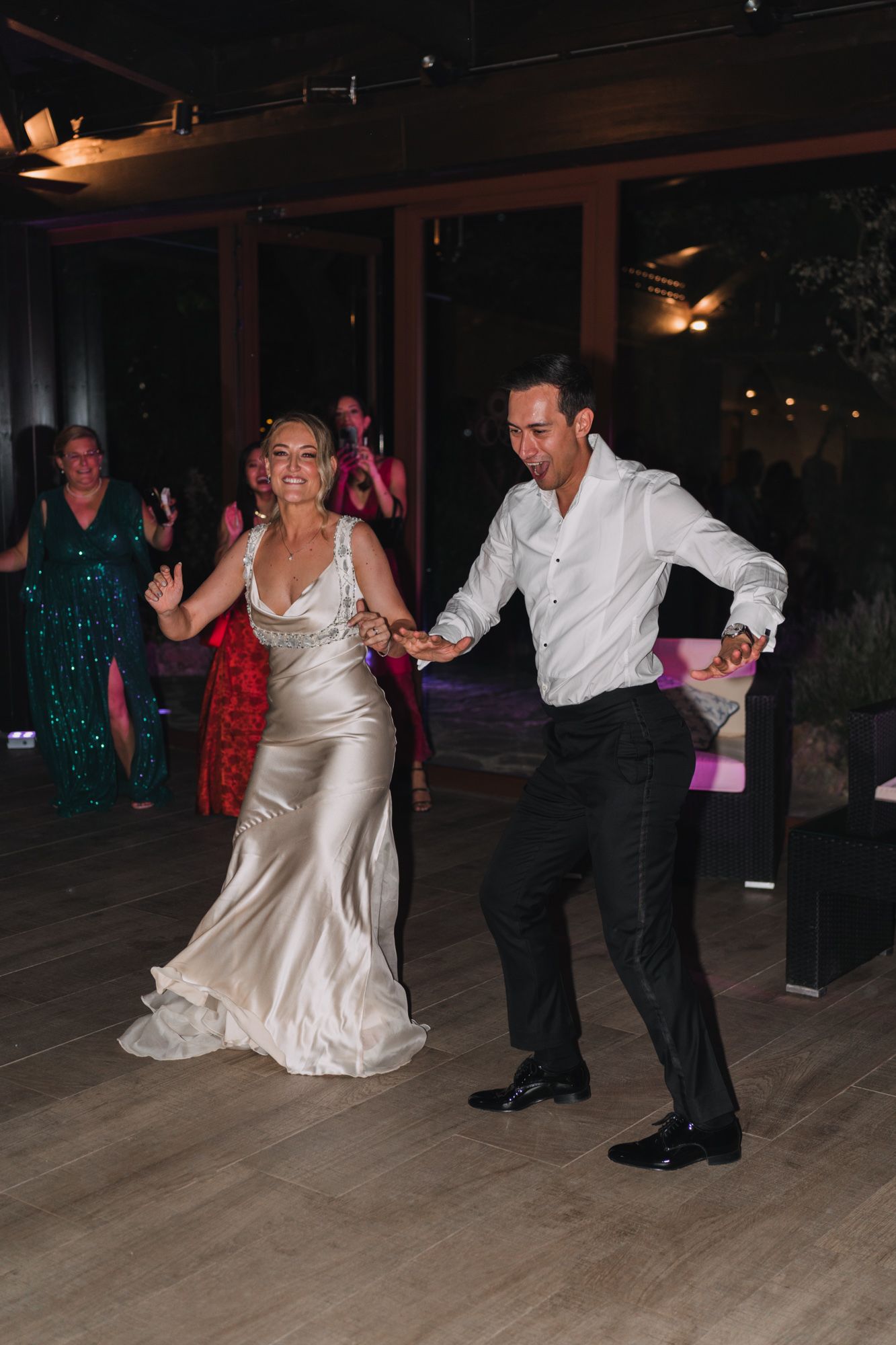 A couple dancing at a wedding reception with the bride wearing a silk champagne gown and groom in dark suit.