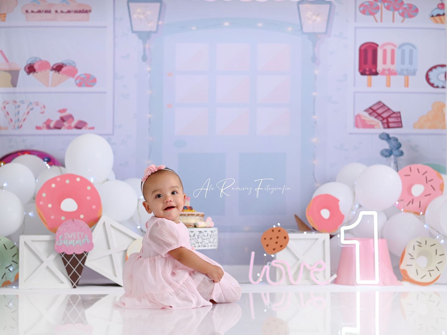 Sweet donut and ice cream themed first birthday party setup with pink and white decorations and balloons.