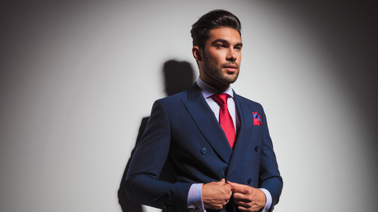 A White male with a complete blue suit, with red tie and red filler for his pocket