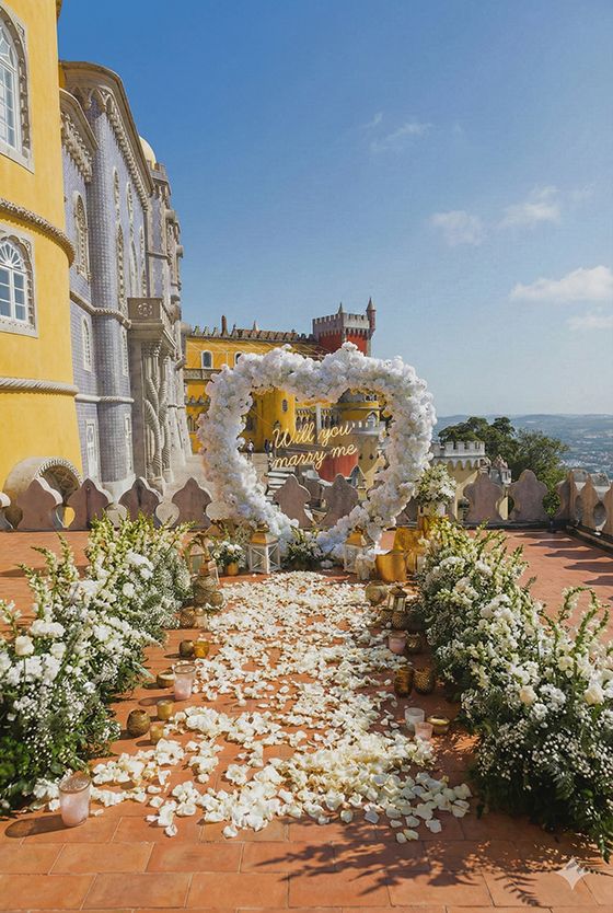 Yellow palace terrace decorated with white floral arrangements and petals against a bright blue sky.