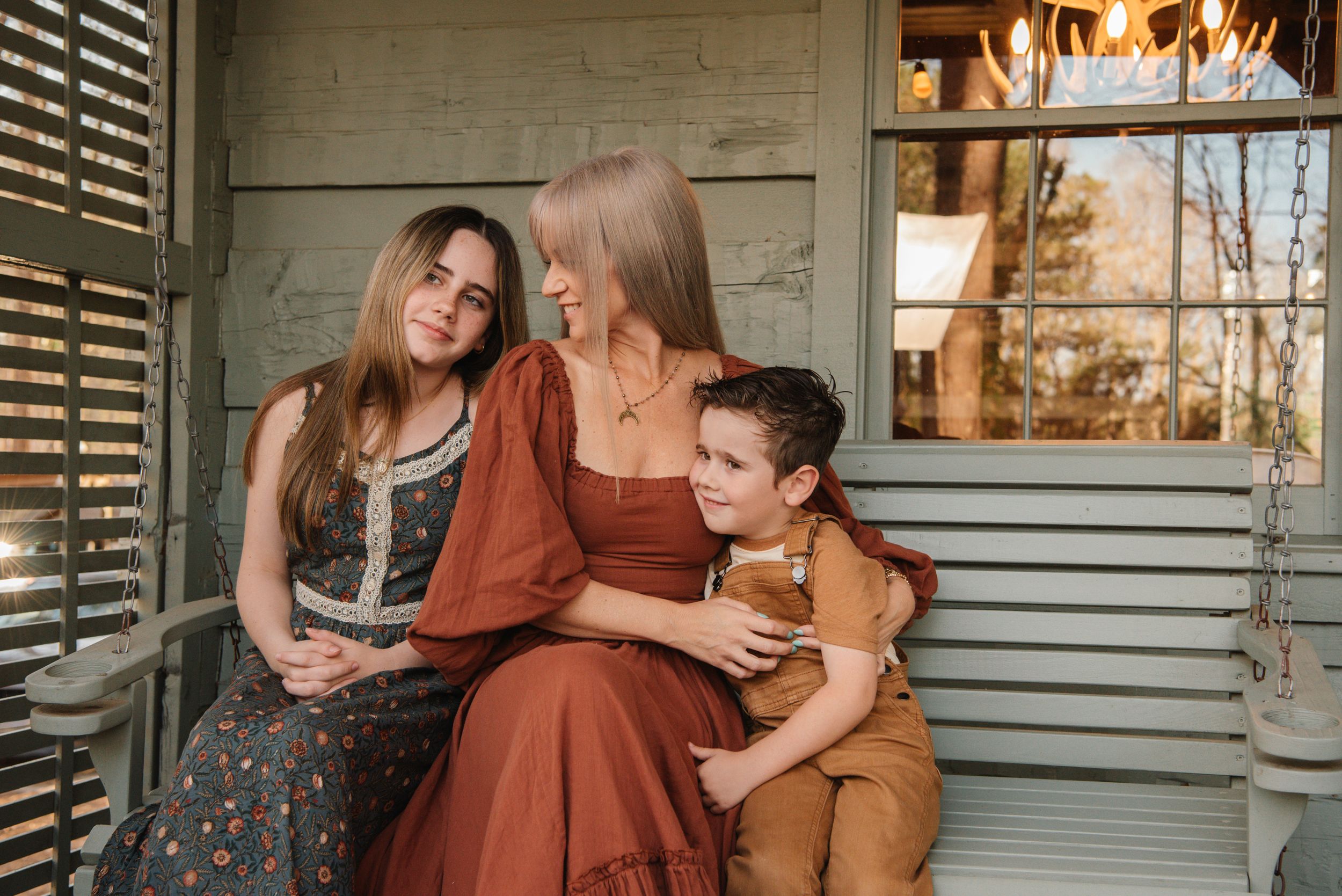 Three people share a casual moment sitting together on wooden steps.
