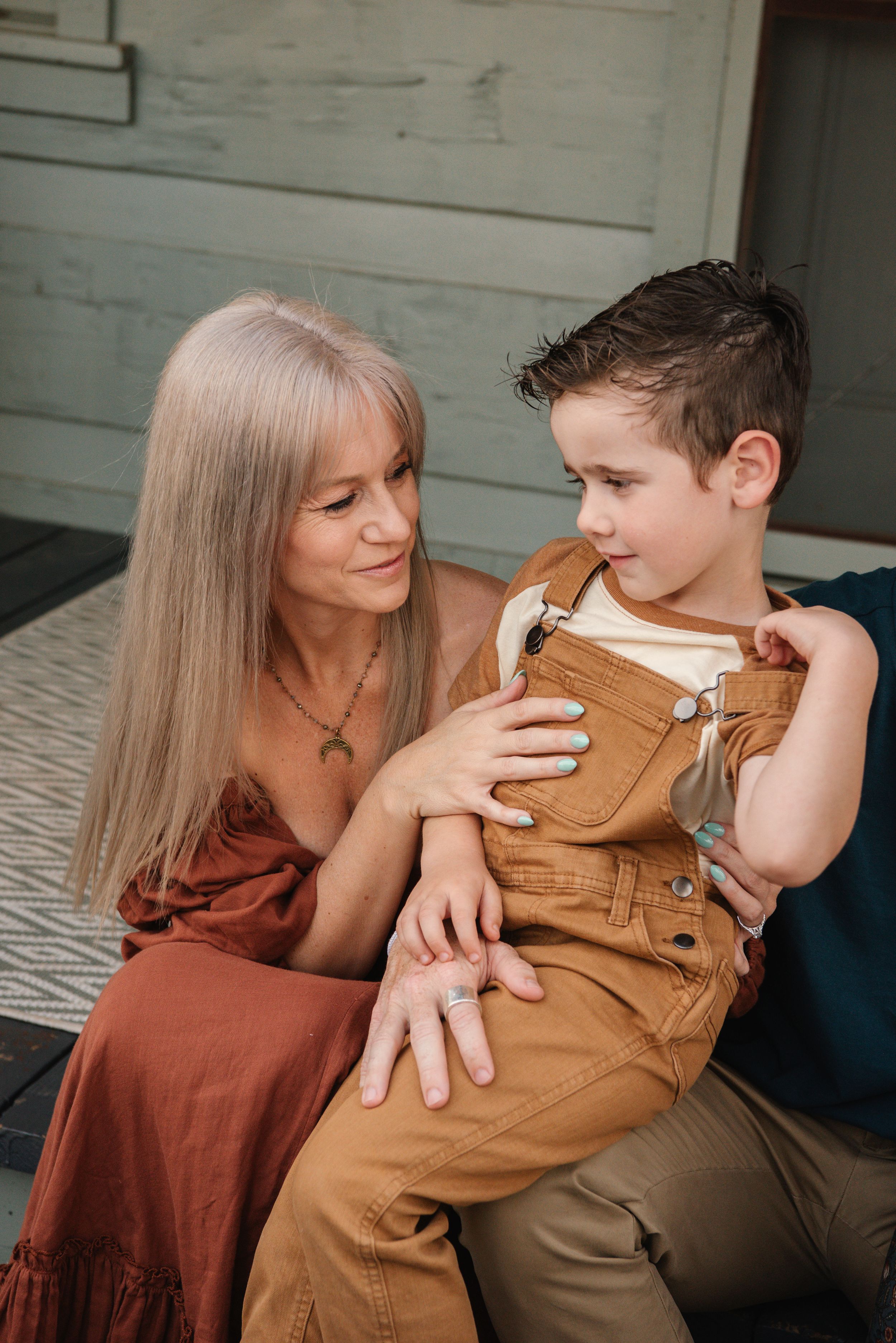 A tender moment captured between two people sitting on wooden steps in warm earth-toned clothing.