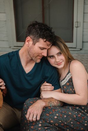 An intimate moment shared between a couple sitting close together on a porch.
