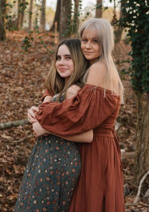 A warm embrace shared between two people in coordinating rust and floral dresses.