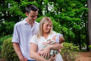 Parents gazing at their newborn baby while standing in a lush garden setting.