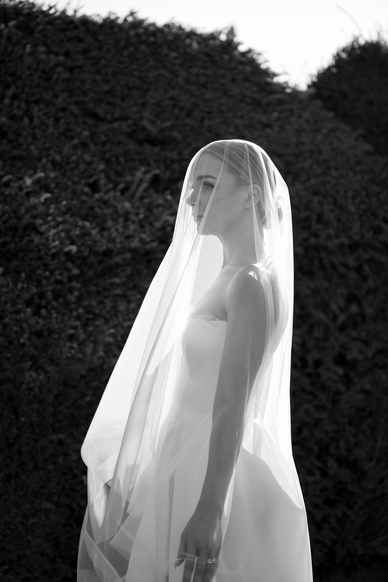 Lake Como bride in all-white ensemble lounges in chair on sunny garden terrace with mountain views.