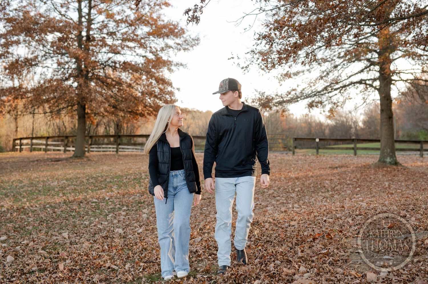 siblings walking hand in hand through fallen autumn leaves in a park setting.