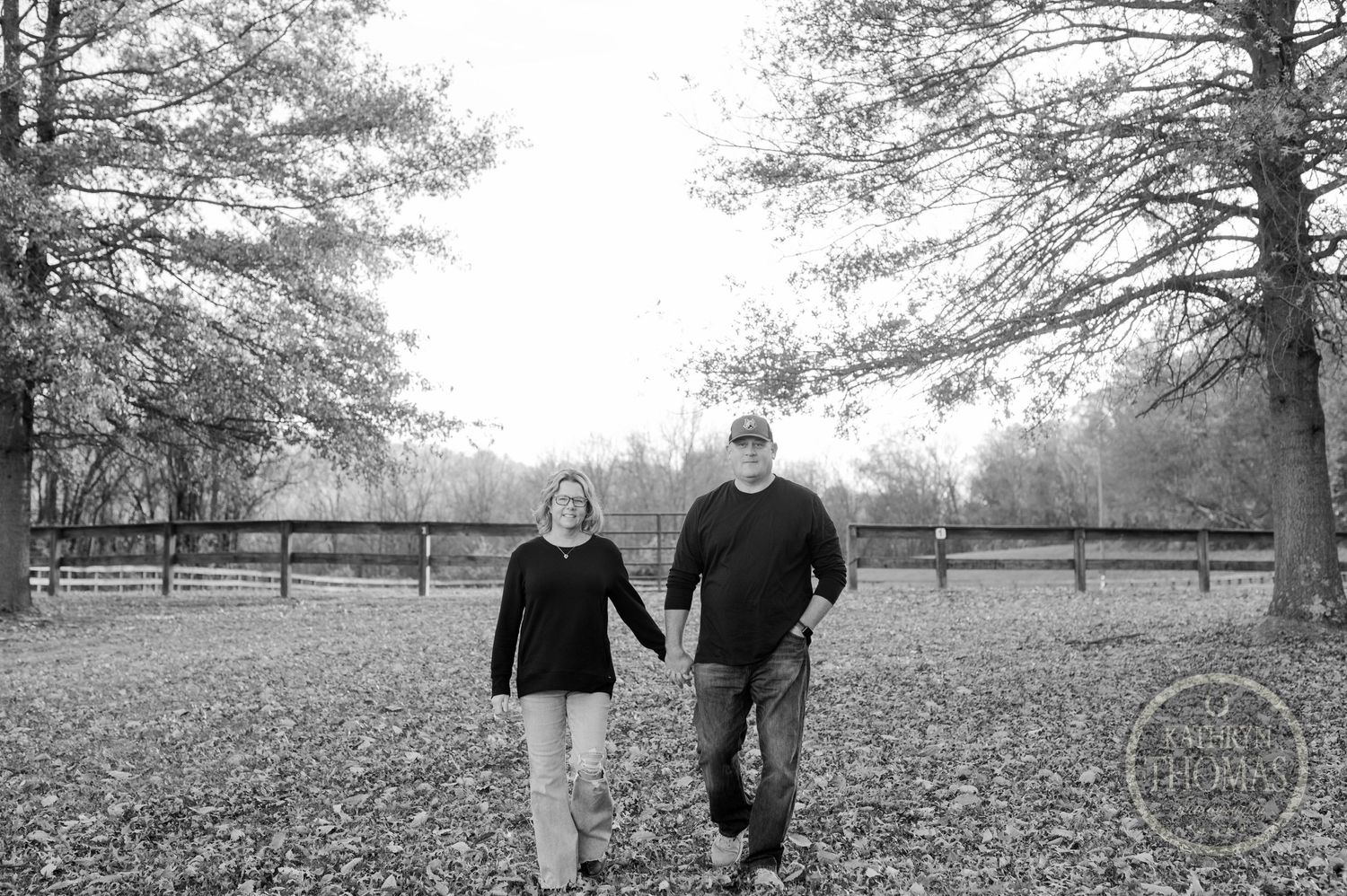 A couple takes a romantic autumn stroll through fallen leaves in a park landscape.