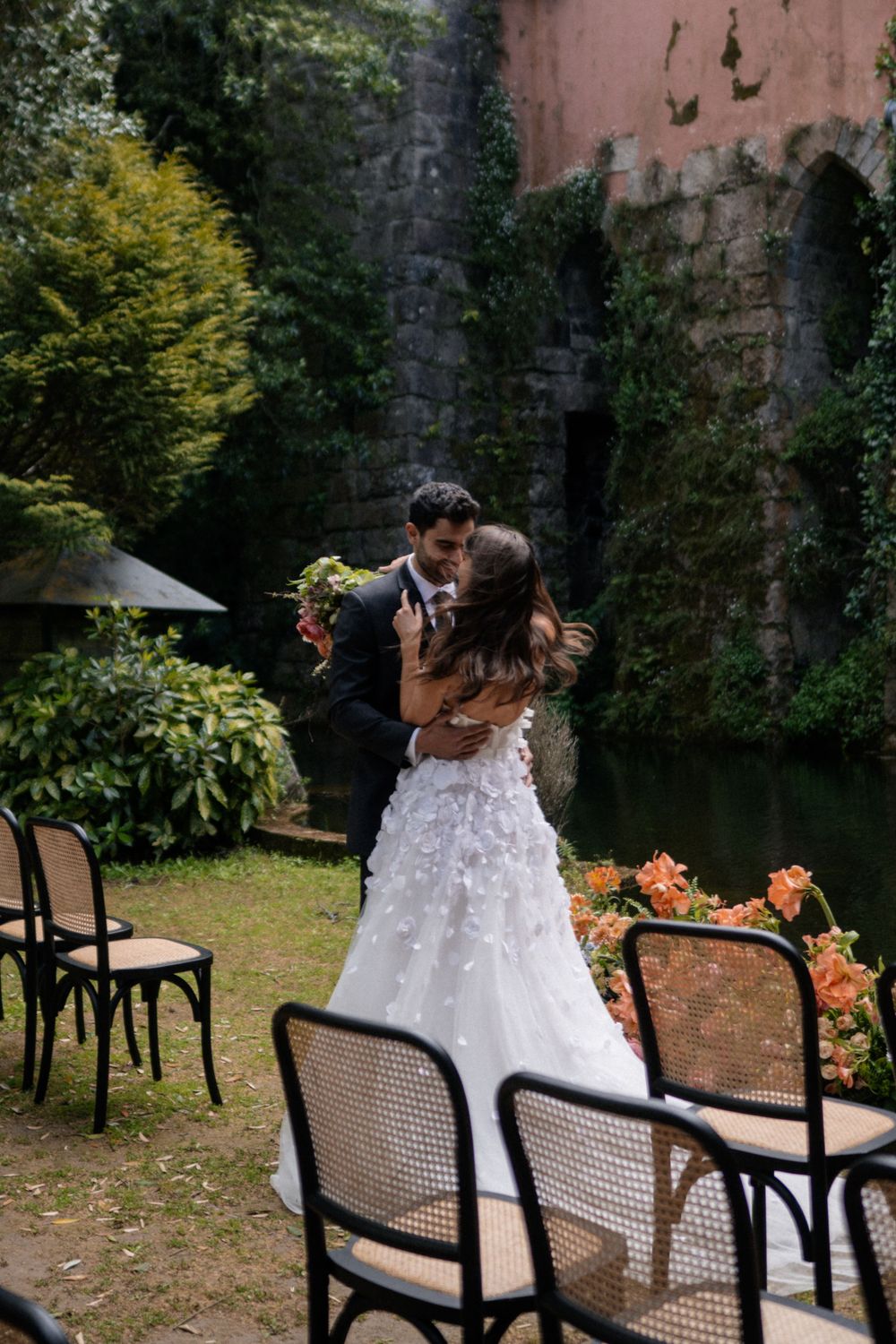 An intimate wedding moment in front of vintage chairs and stone archways with climbing ivy.