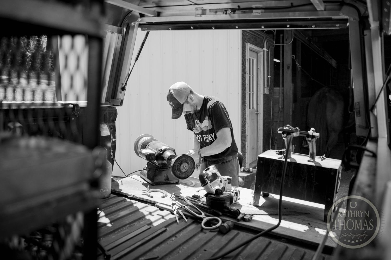 Black and white photo of farrier work being done in a mobile workshop.