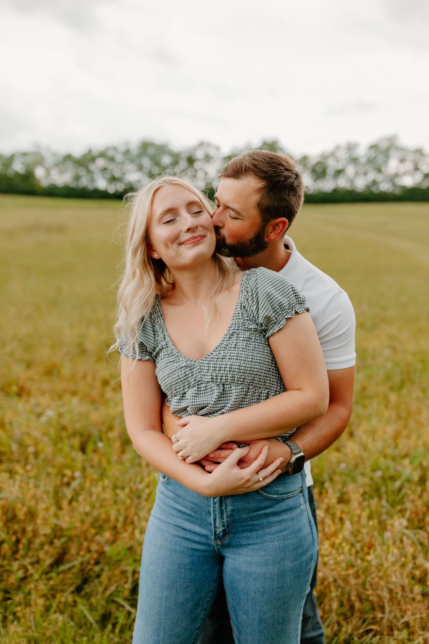 Intimate couple embracing in golden field during sunset photoshoot.