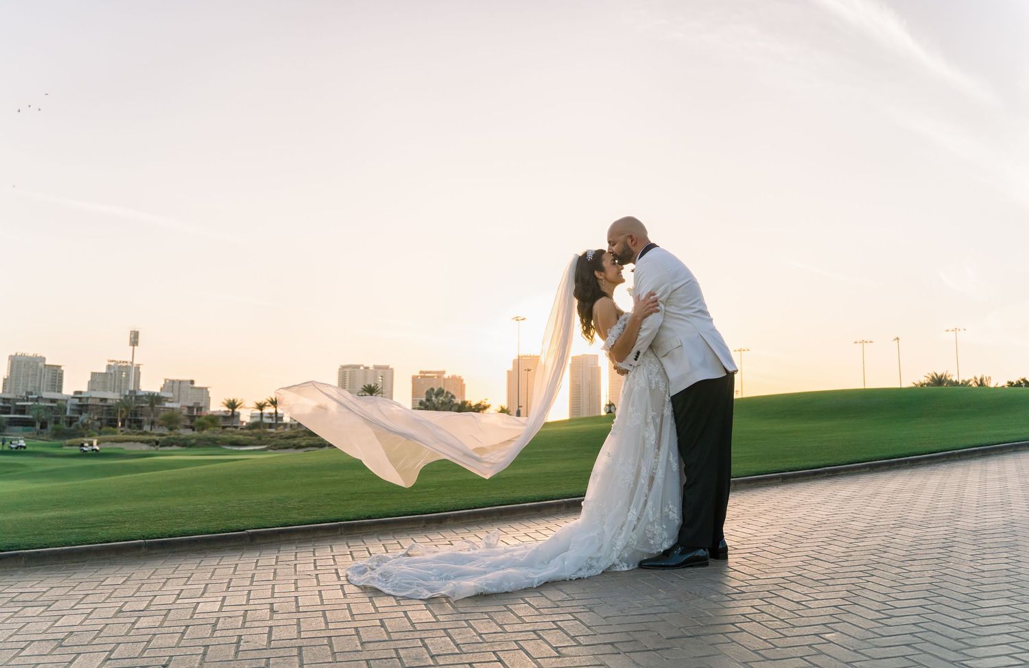 A celebratory wedding moment as newlyweds walk under twinkling lights while performers in elaborate costumes entertain guests.