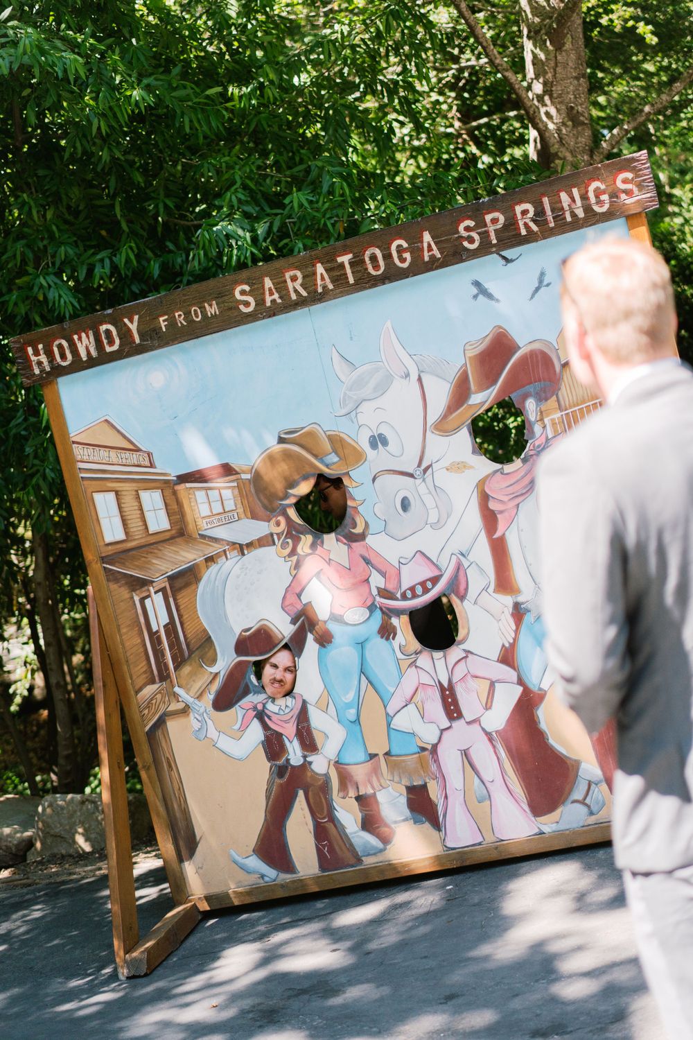 Photo booth backdrop at Saratoga Springs featuring a whimsical vintage-style cowboy illustration with 'Howdy' text.
