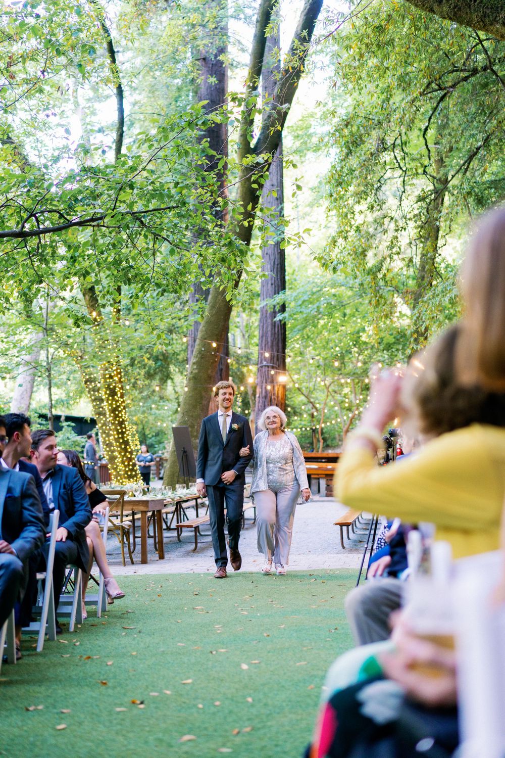Outdoor wedding ceremony setting with string lights and trees creating a natural canopy.