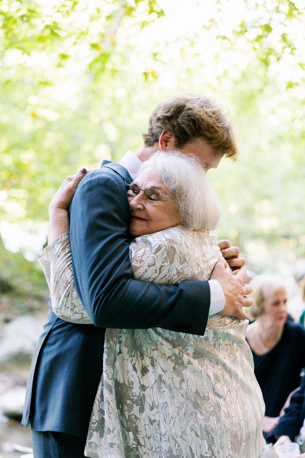 A tender moment between two people sharing a warm embrace at an outdoor gathering with soft bokeh lighting.
