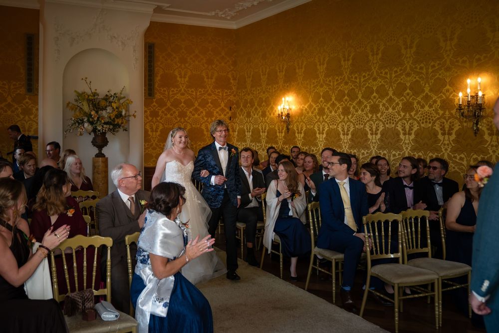 Een bruiloft loopt met haar vader door het gangpad naar haar bruidegom tijdens haar bruiloft in kasteel Ruurlo.