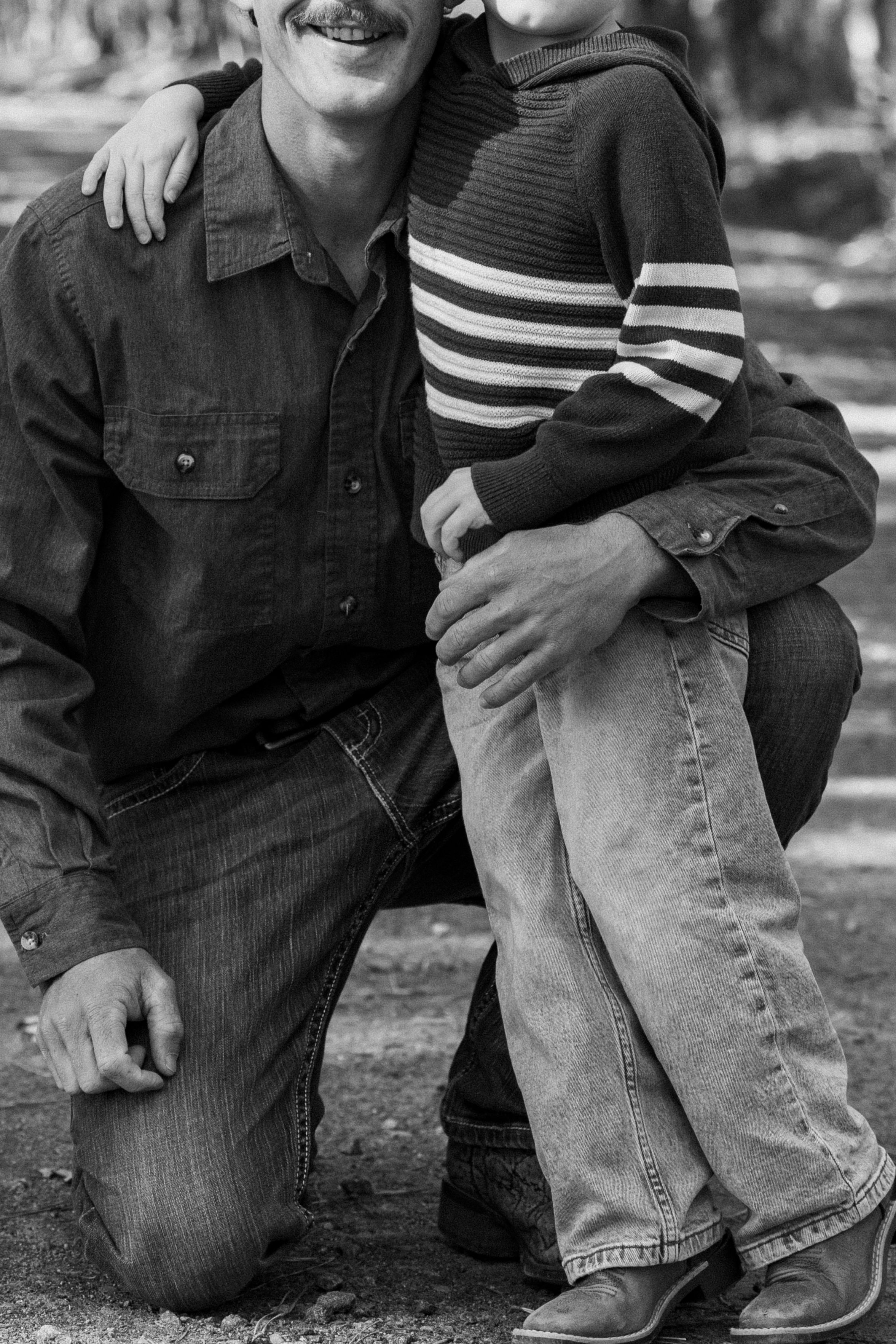 Black and white photo showing close-up of casual denim clothing and a striped sleeve in an outdoor setting.