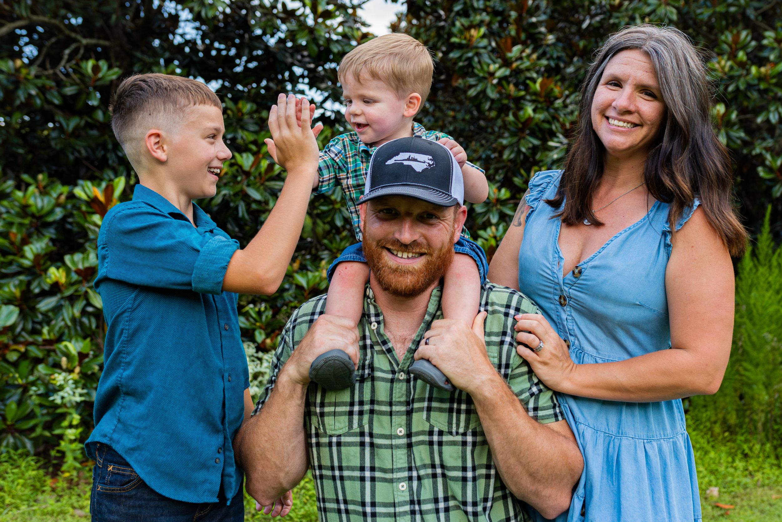 A candid outdoor family photo series with playful interactions against a green leafy background.