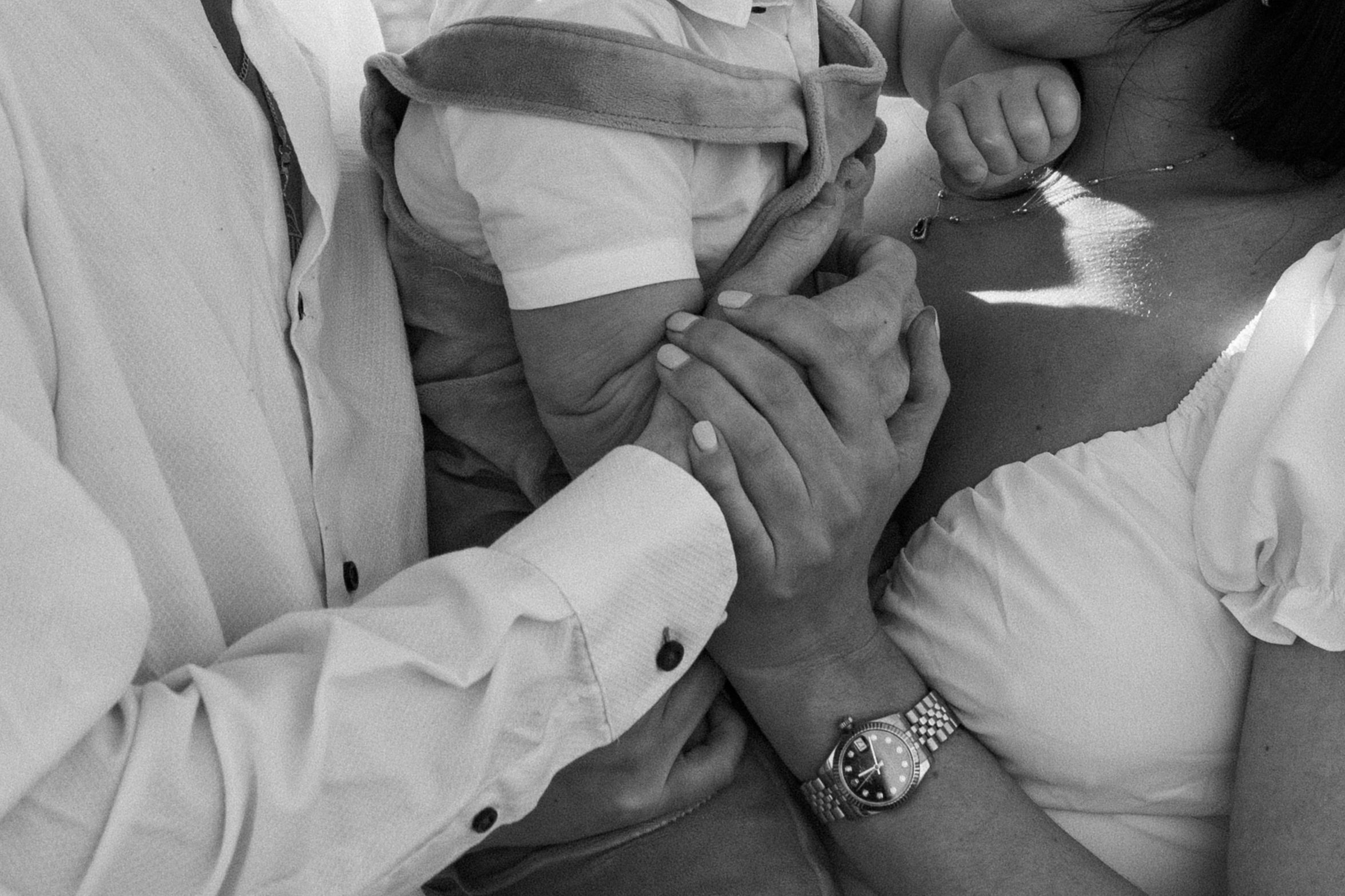 Black and white image showing tender moment of hands holding and touching in formal attire.