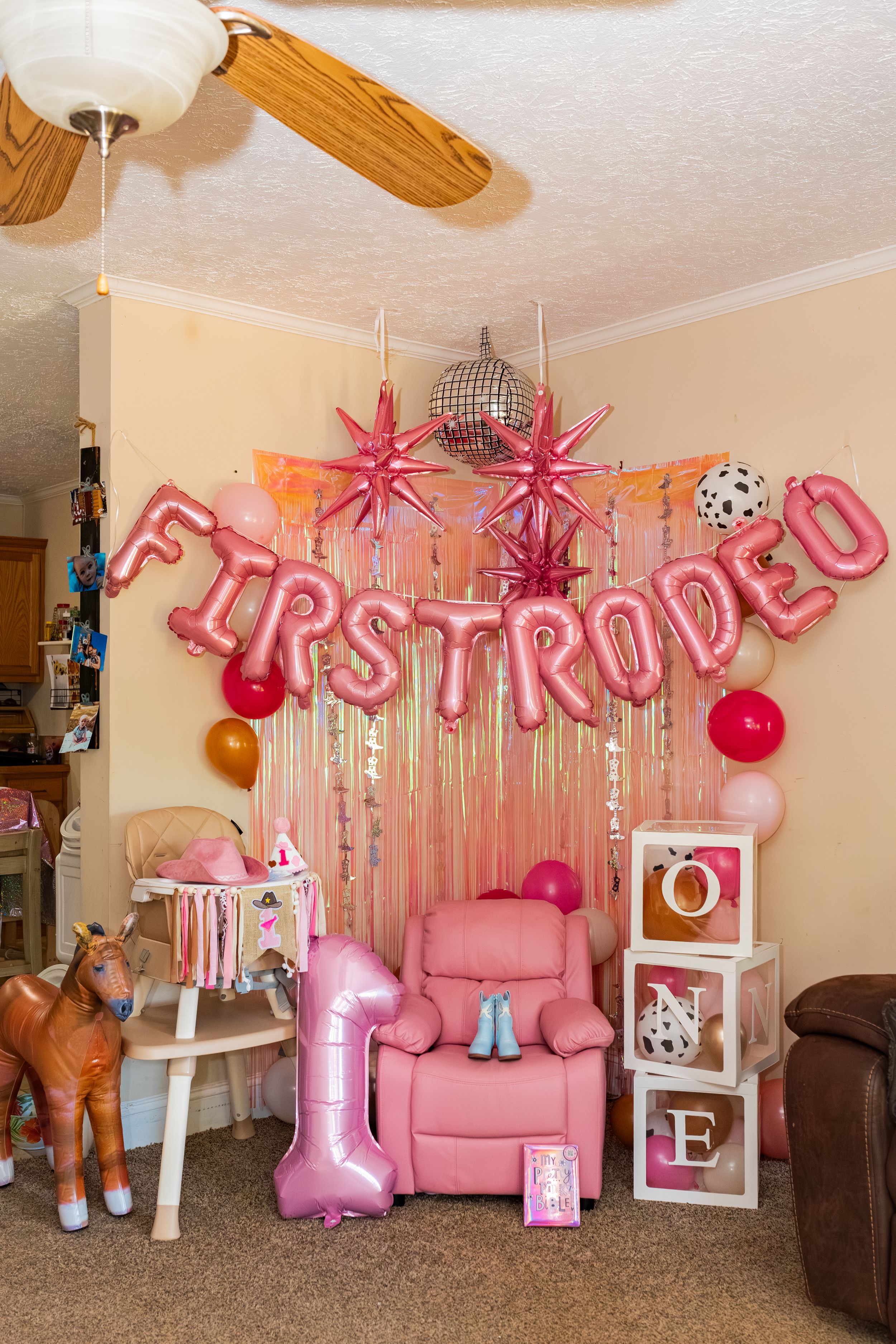 Pink first rodeo birthday party decor with balloon letters, disco ball, star decorations, and ONE blocks for a 1st birthday.