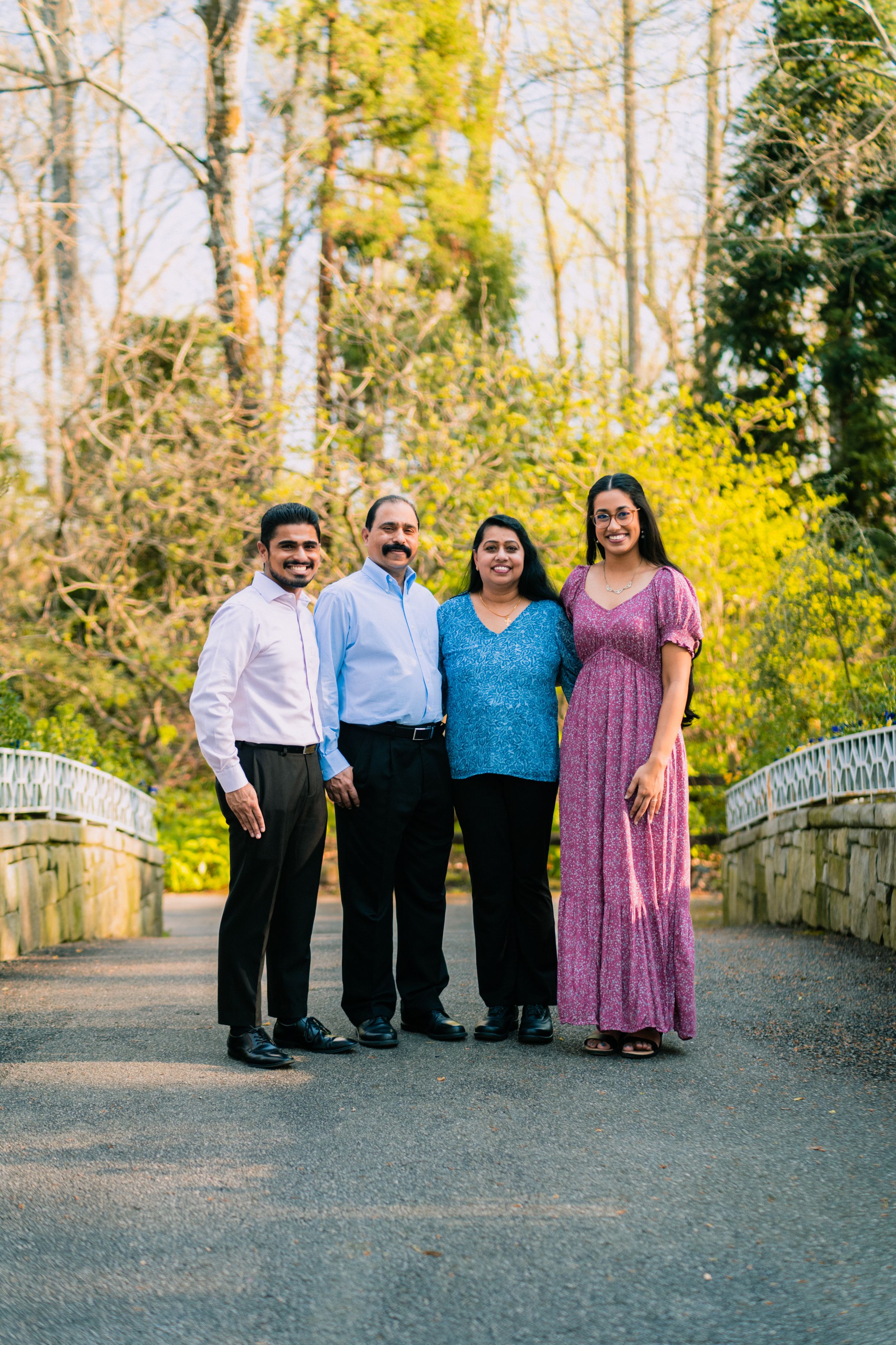 A group stands together on a stone bridge path surrounded by bright yellow forsythia blooms and spring trees.