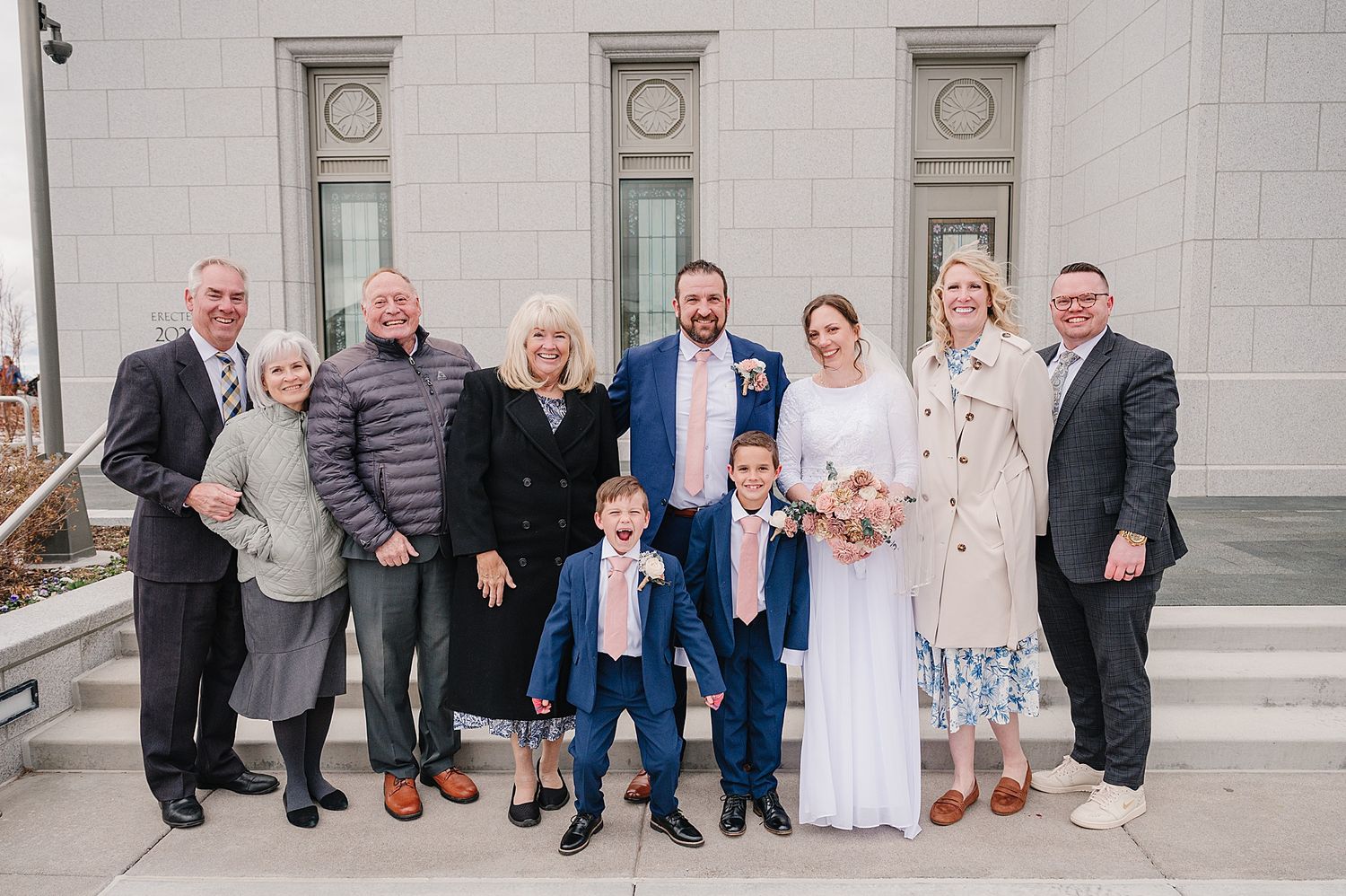A group stands together on white stone steps outside a building with classical-style architecture.